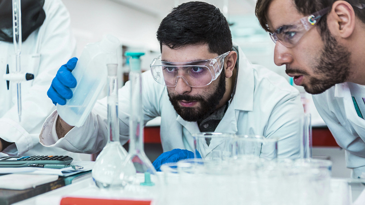 Students pouring chemicals into a beaker