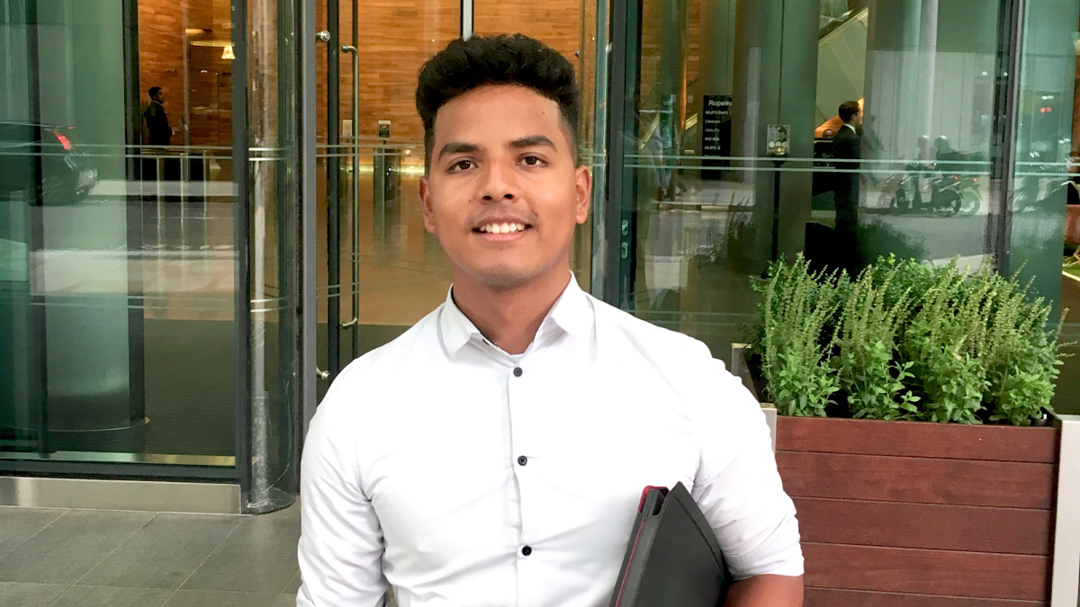 Freddy Farias Arias smiling in front of modern building